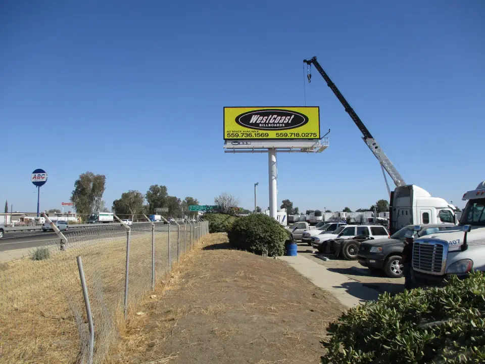 WestCoast contact billboard beside a truck lot and Highway 99
