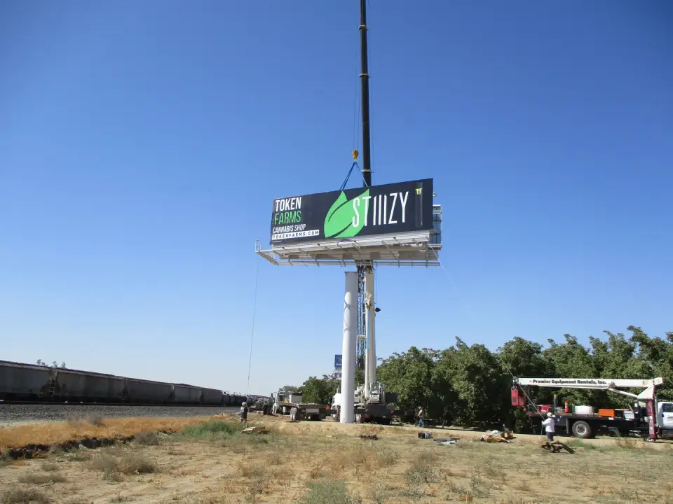 Crew on a lift servicing a billboard beside Highway 99