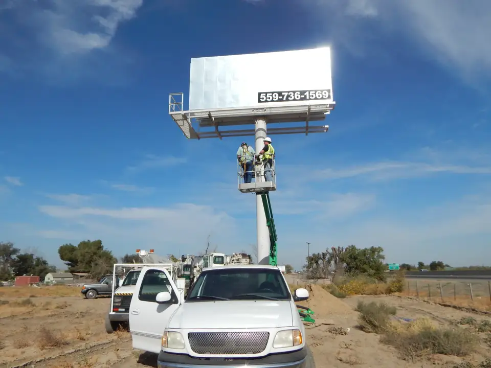 Lift crew working on a blank billboard beside Highway 43